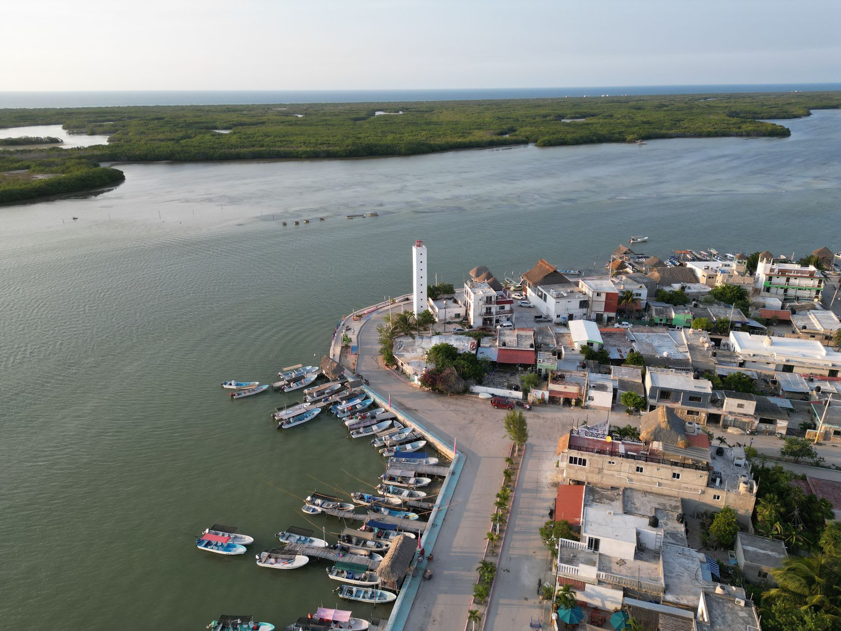 The central plaza and colonial church of Mexcaltitán at low water, the concentric circular streets of the island village visible in the late afternoon light, fishing boats moored at the dock, the Nayarit lagoon surrounding the circular island