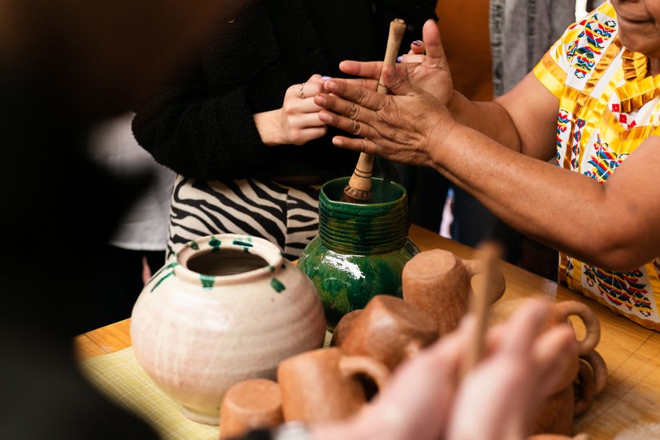 Clay copitas of mezcal lined up on a wooden table at a Oaxacan mezcal stall