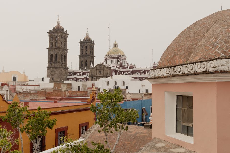 The baroque towers of San Francisco de Asís rising above the Pabellón de Arteaga rooftops against a clear blue sky