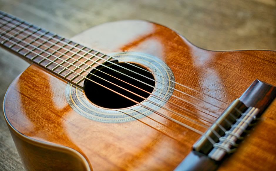 Finished classical guitars lined in a Paracho shop window, their lacquered bodies reflecting the pale highland sky