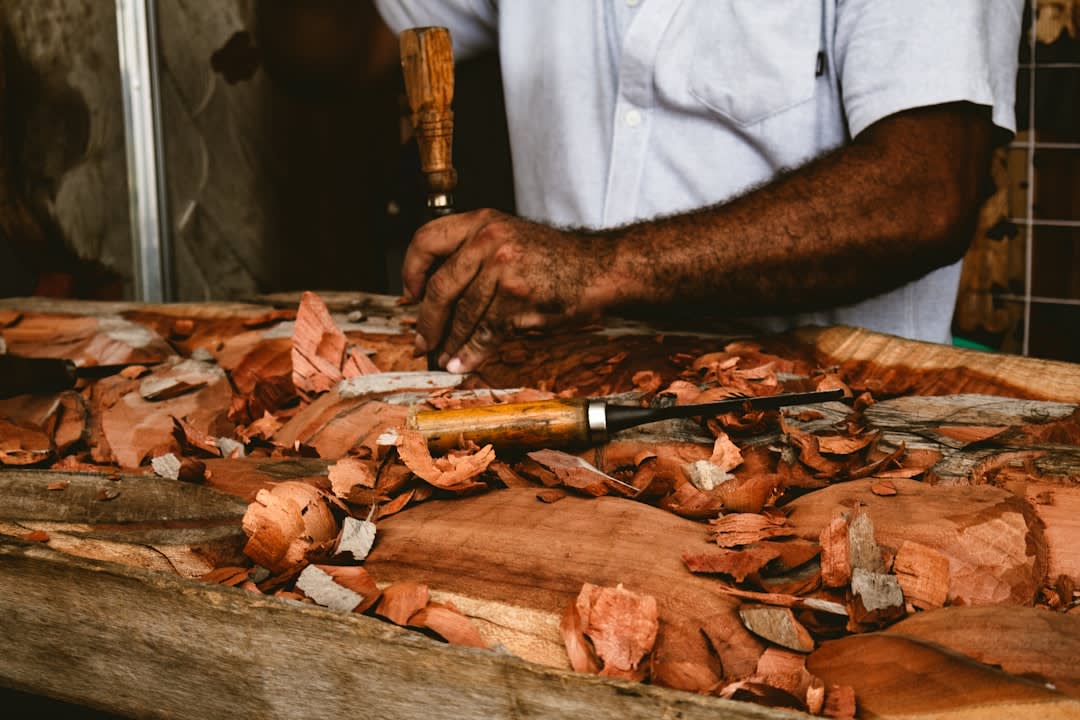 The interior of a Paracho guitar workshop, multiple classical guitars in various stages of construction, the cedar tops and rosewood sides visible, the master luthier examining the bracing pattern of a soundboard, finished instruments on the wall behind