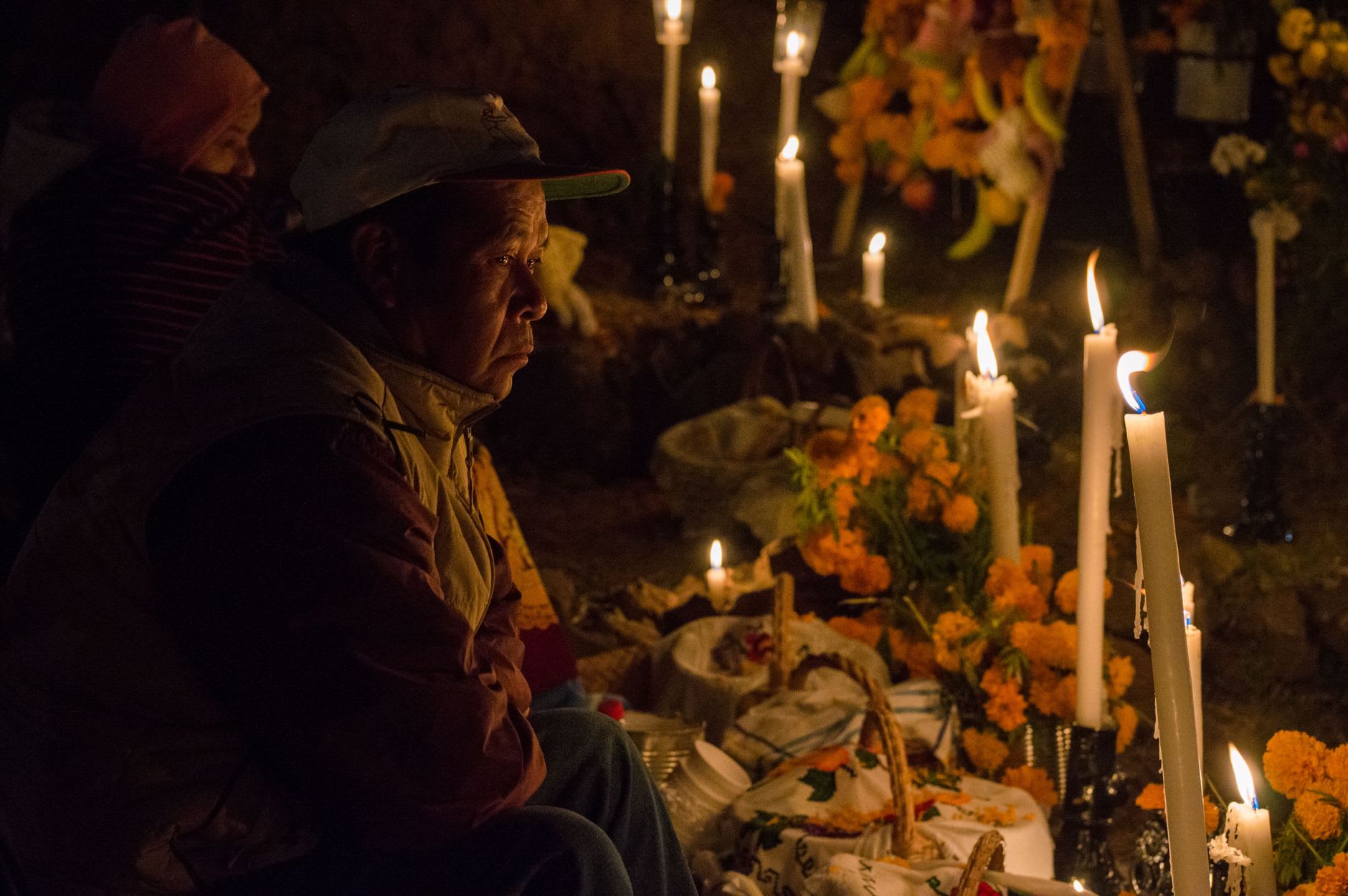 Hundreds of candles and marigold offerings covering the graves in the cemetery of Janitzio island, families in vigil through the night of Día de Muertos