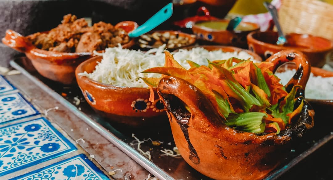 A market stall in Puebla's El Alto market with colorful chiles, mole ingredients and Talavera pottery, the vivid reds and greens of dried peppers filling the foreground