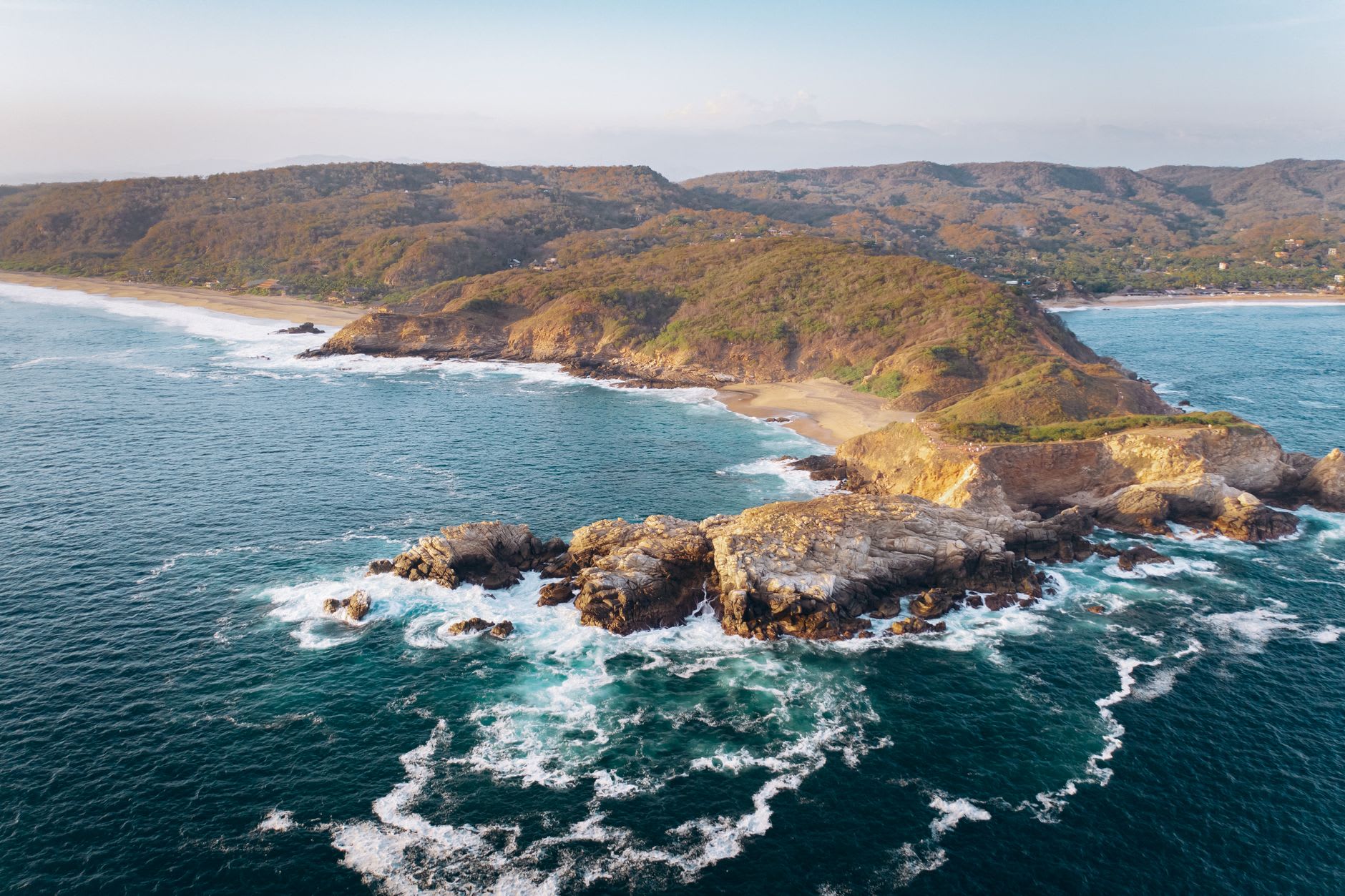 A panga heading toward the Marieta Islands from Punta Mita, the rocky island formations ahead, a humpback whale spout visible off to the left, Banderas Bay deep blue in the January light