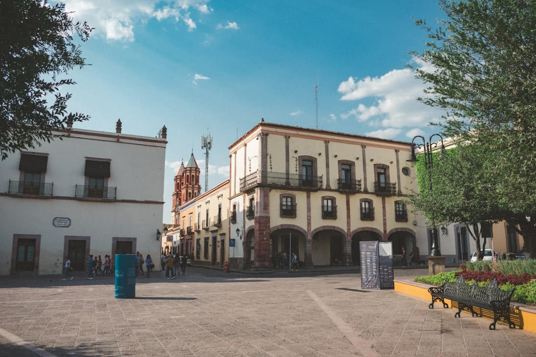 The facade of the Templo de Santa Rosa de Viterbo in Querétaro, its distinctive double flying buttresses and eccentric baroque towers in pink stone, bougainvillea against the wall below