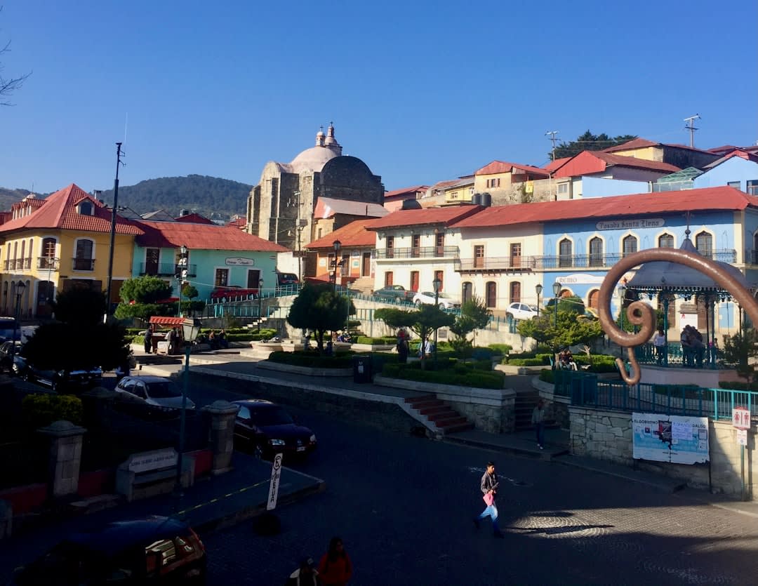 The hillside mining town of Real del Monte on a misty afternoon, the 19th-century church tower above the colorful houses on the steep slopes, the old mine headframe visible on the mountain above the town