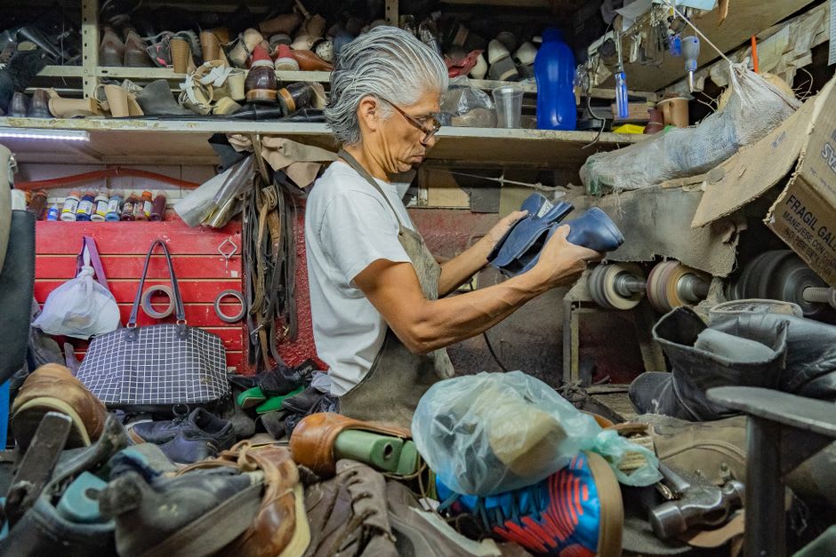 Artisan leather boots arranged on a workshop bench, tools and cut hides visible in the background