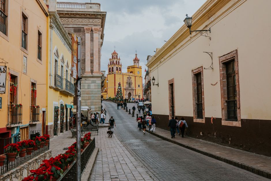 The Parroquia de San Francisco de Asís seen from the main plaza on a Sunday morning, a few worshippers descending the stone steps