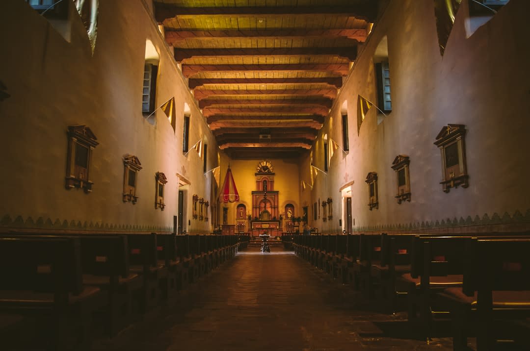 The interior nave of Misión San Javier, oil paintings visible in the dim transept