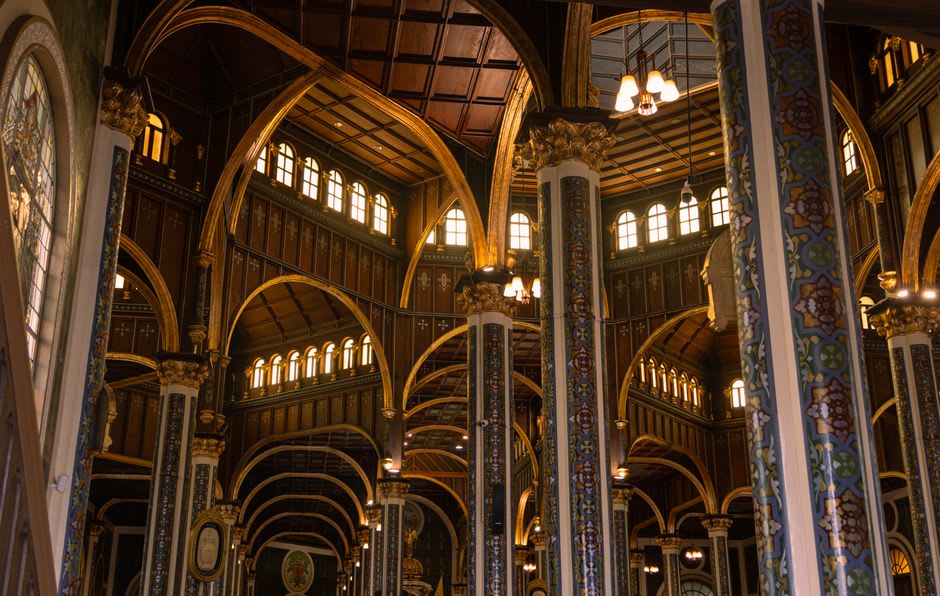 The gilded retablo interior of the basilica in San Juan de los Lagos, candlelight reflecting off carved gold leaf and rows of milagrito offerings