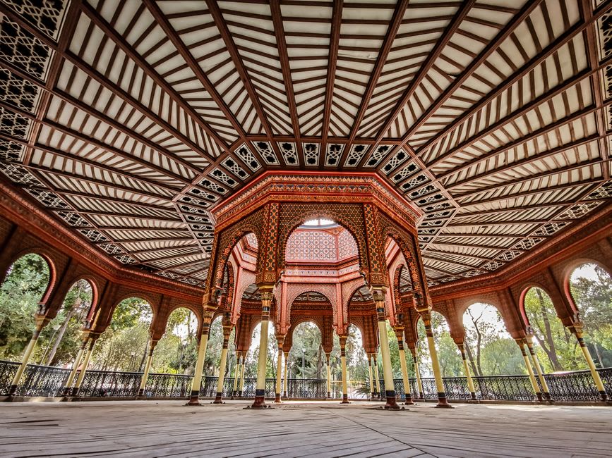 The Kiosco Morisco rising above the Alameda de Santa María, its ornate horseshoe arches and tilework visible through the surrounding jacaranda trees