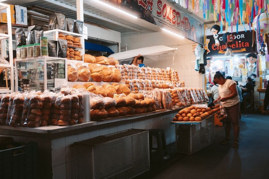 The storefront of Panadería El Boleo with morning light and a short queue of locals