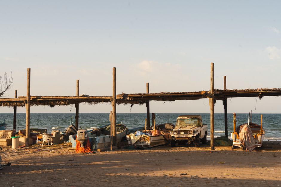 The malecón of Seybaplaya at golden hour, old men fishing from the railing as the Gulf turns bronze