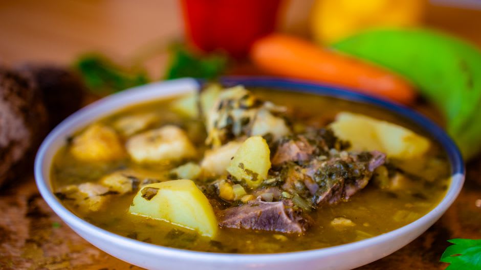 Steaming bowls of birria de res with consomé and warm tortillas at a Tepatitlán birriería