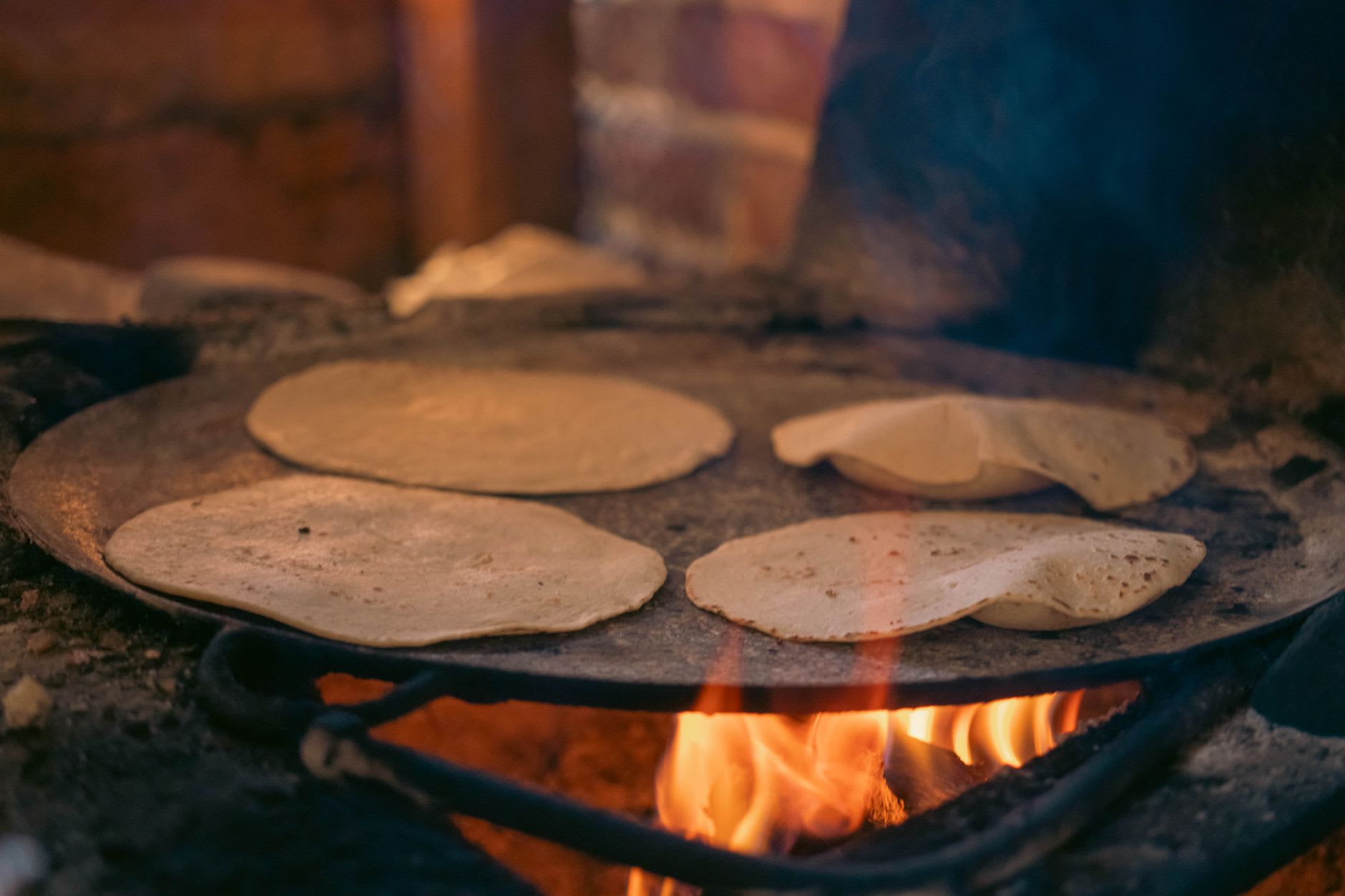 A Sunday market stall in Tepoztlán with dried chiles, herbs, and fresh tlayudas cooking on a clay comal