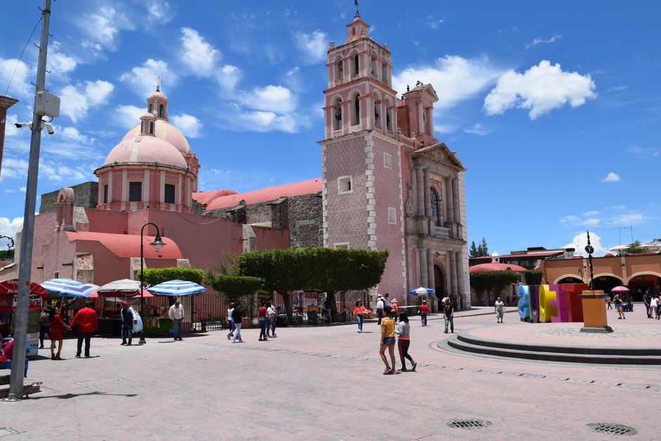 The weekend market on Tequisquiapan's main plaza, local cheese and produce vendors in front of pink stone colonnaded buildings