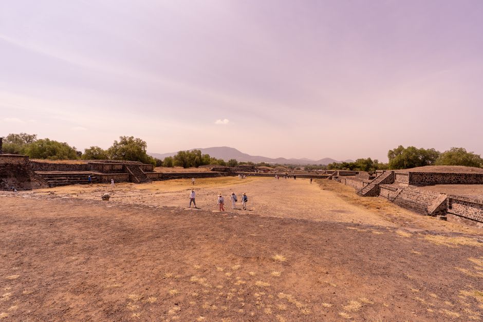 Circular tiers of the Guachimontones pyramid seen from the access path, stone terraces framed by green valley and blue sky