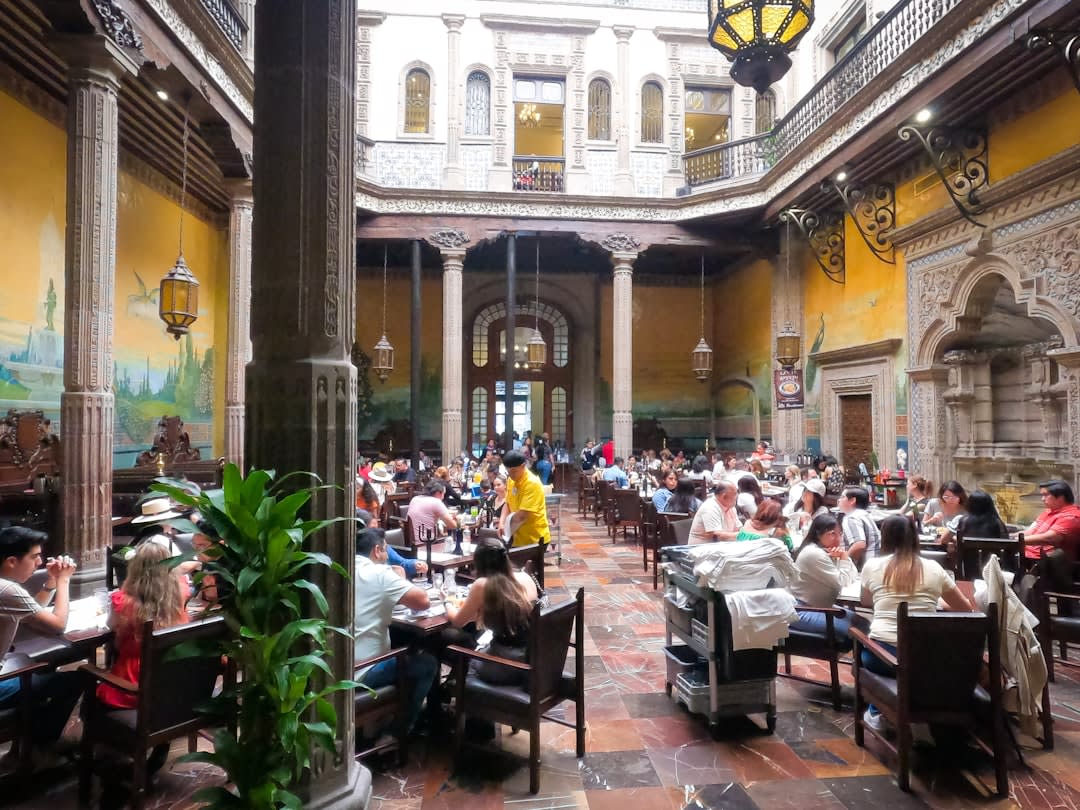 El Parián in Tlaquepaque, its colonial courtyard filled with mariachi musicians and families at communal tables eating birria and drinking tequila on a Sunday afternoon