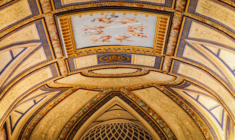 Detail of the Tonantzintla nave ceiling showing polychrome stucco cherubs with indigenous faces amid corn and tropical birds in gold and turquoise
