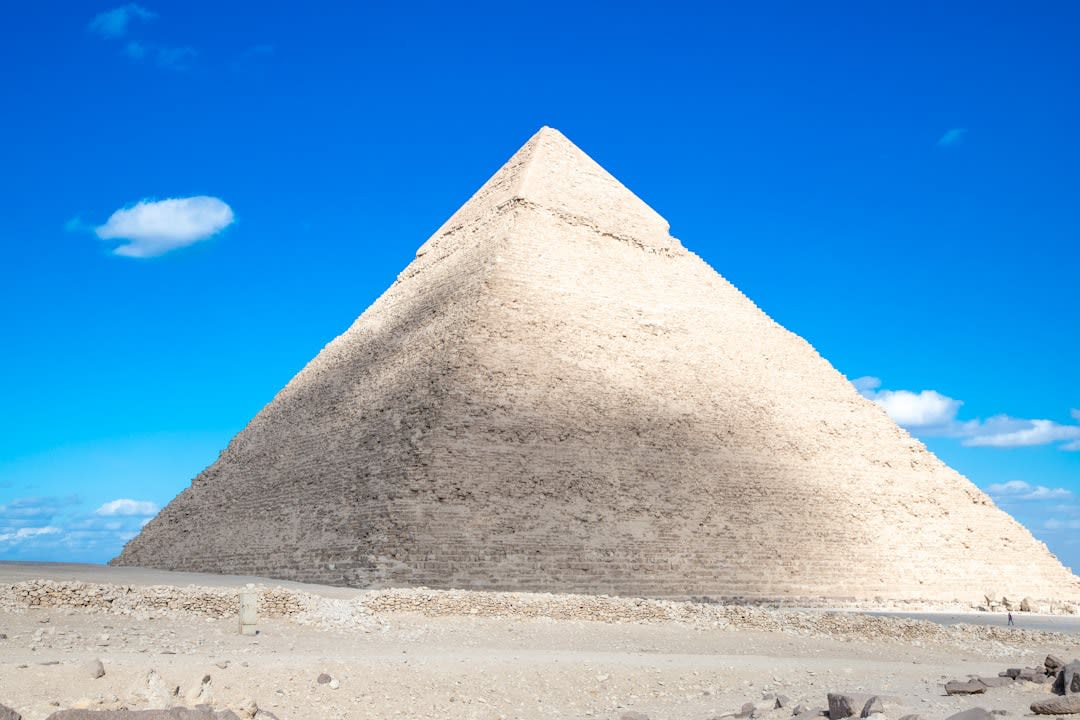 The oval-based Pyramid of the Magician at Uxmal rising above the Yucatán jungle, its five construction phases visible in the layered stone, dawn light on the mosaic facades