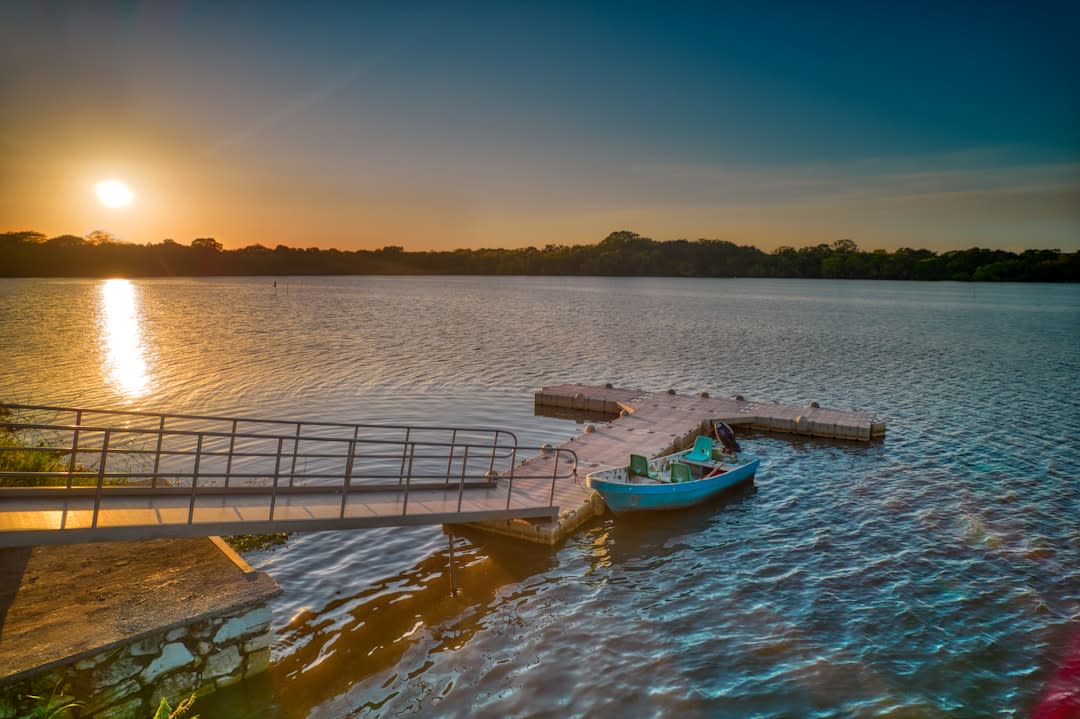 The fiberglass boat on the Río Usumacinta approaching Yaxchilán, the Maya ruins visible emerging from the Lacandon jungle on the left bank, the Guatemala shore on the right, the river green in the morning light
