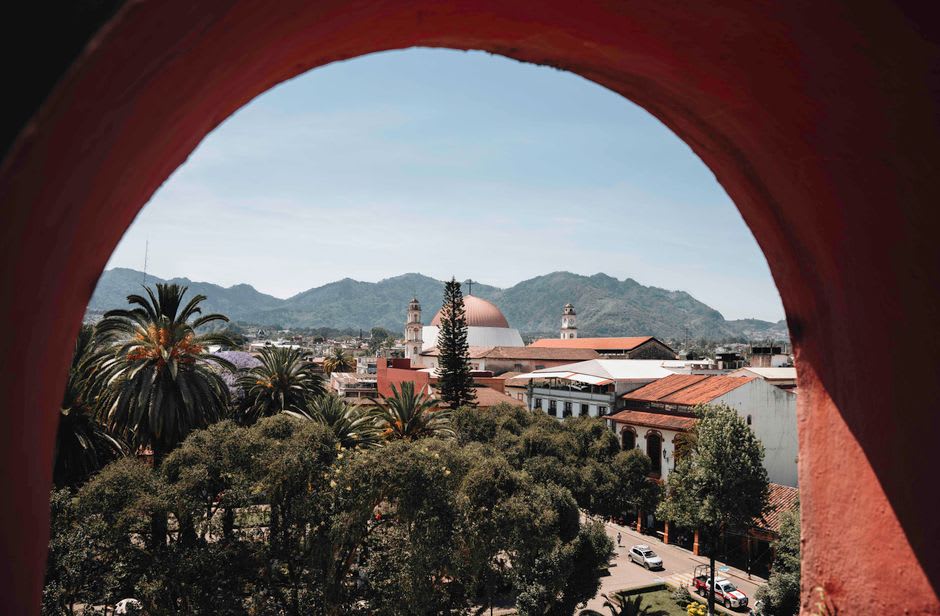 The colonial church and presidencia municipal of Zacapoaxtla face each other across the central plaza on a mist-softened morning