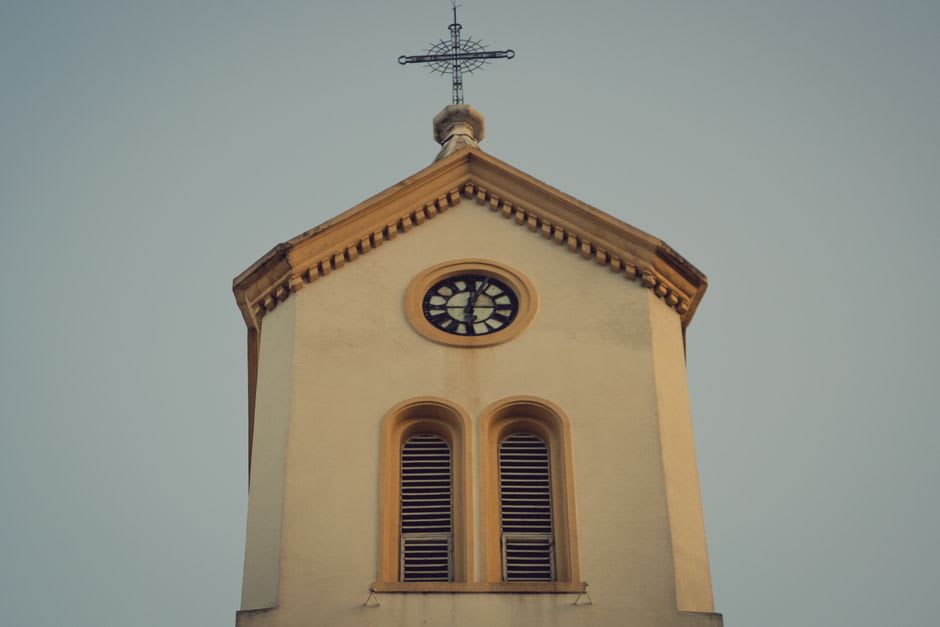 The mechanical clock tower of Zacatlán's main church, wooden figures visible in the upper section against a blue sierra sky