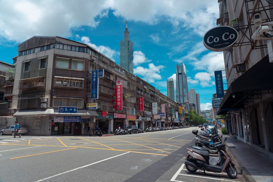 A quiet street in downtown Koror with local shops, parked scooters, and laundry hanging between buildings