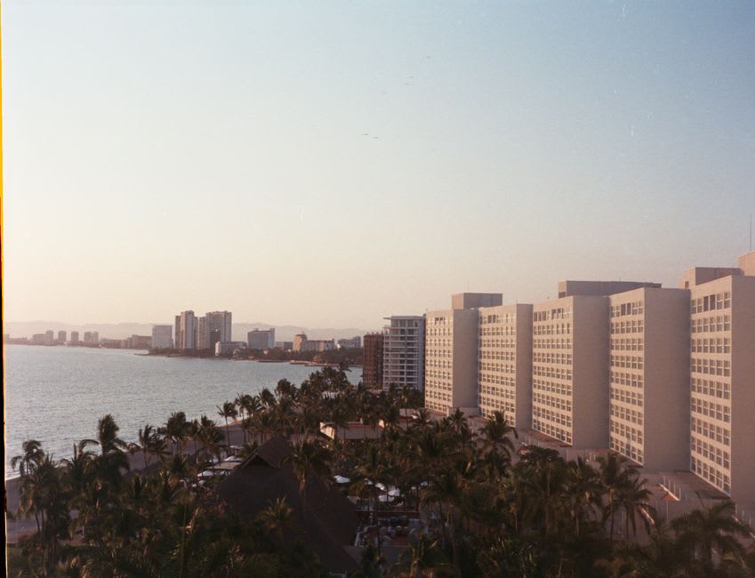 High-rise resort hotels lining the curved white sand shoreline of Tumon Bay at sunset
