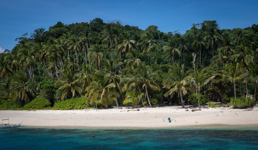 A traditional outrigger canoe pulled up on the white sand of a Ulithi Atoll islet at low tide
