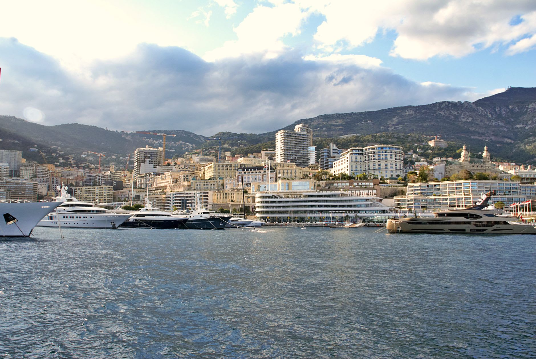 The wide industrial boulevard of Fontvieille with a classic car workshop and Monaco's cliffs visible at the end of the street