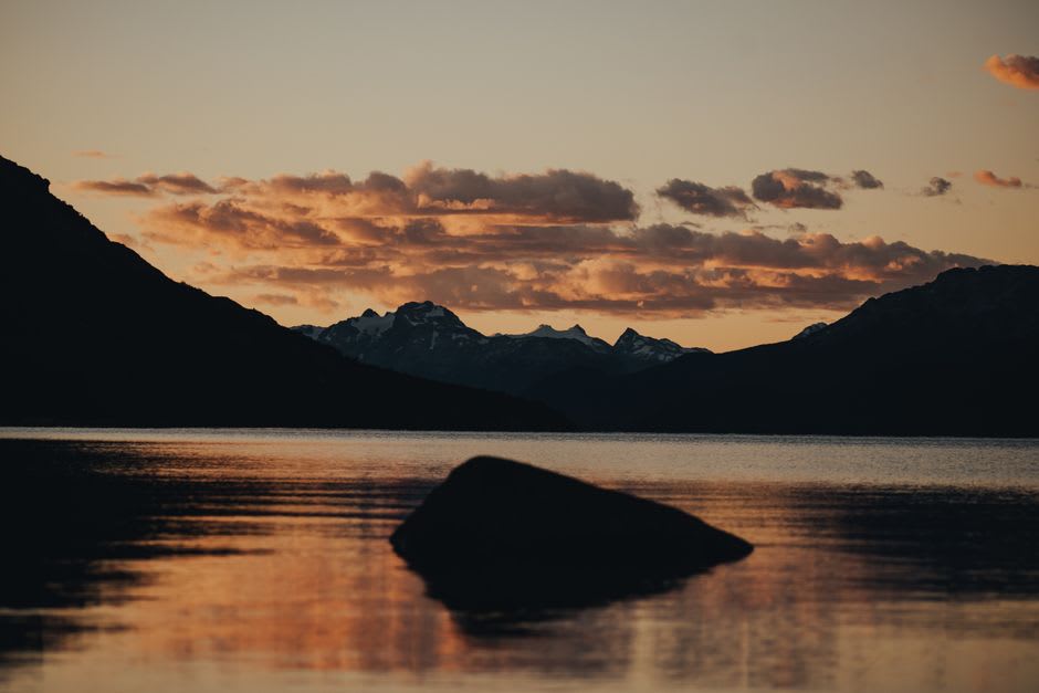 A herd of horses grazing along the grassy shoreline of Telmen Lake at sunset