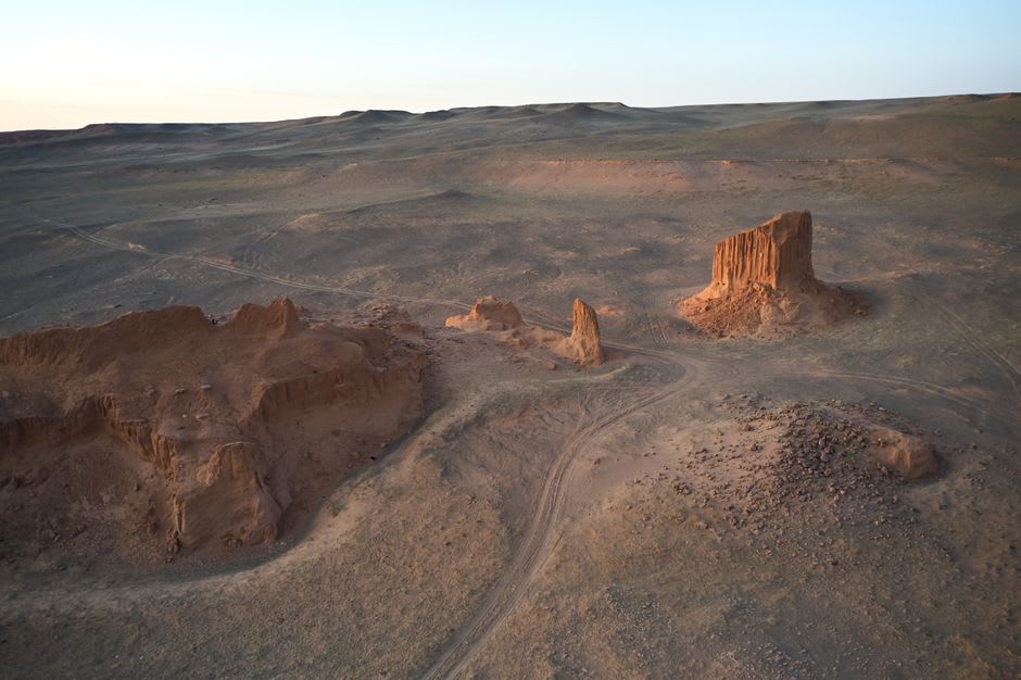 La paroi de falaise sédimentaire en couches de Tsagaan Suvarga captant une lumière orangée profonde au coucher du soleil
