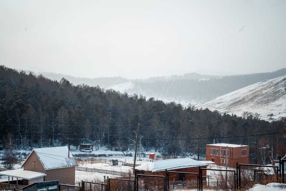 Snow-dusted steppe hills surrounding the hot spring valley under a dramatic dusk sky