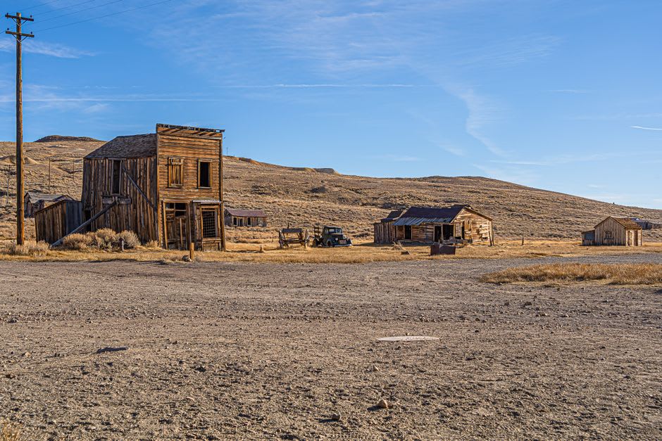 Golden late-afternoon light hitting the dirt road and false-front buildings of Bannack ghost town