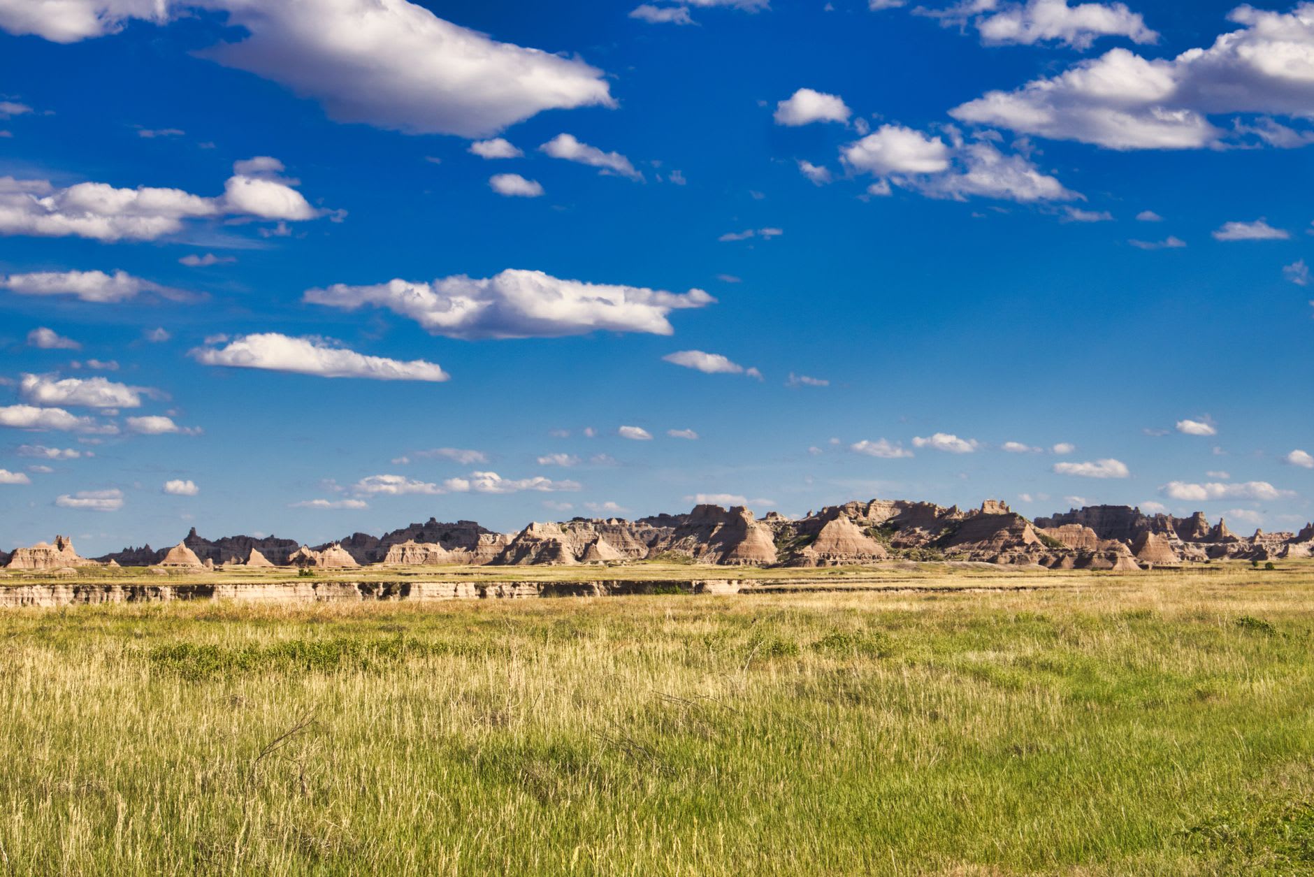 A winding park road climbing through eroded badland formations at Makoshika State Park in warm evening light