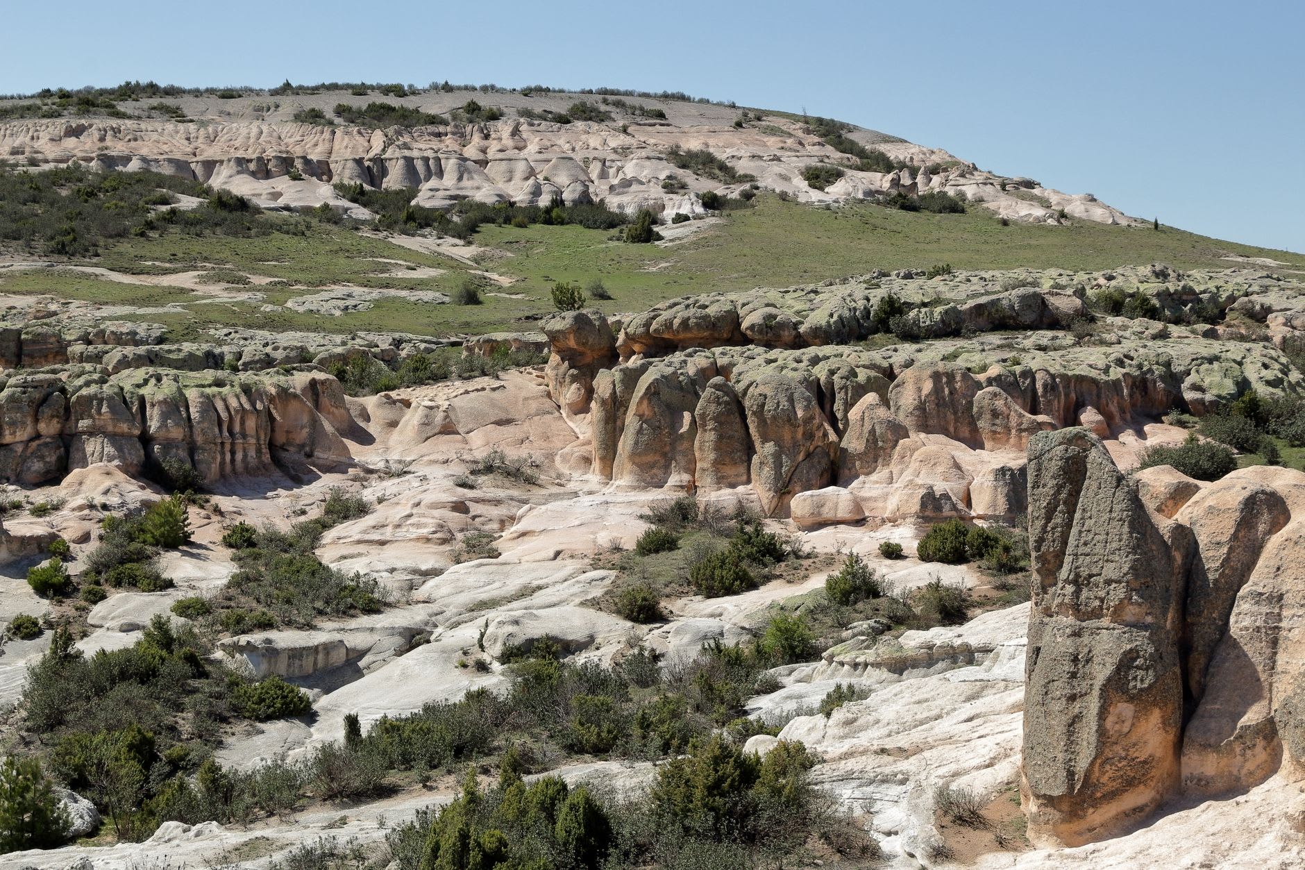 A natural rock bridge and tall eroded pinnacles along a footpath at Makoshika State Park with sparse juniper