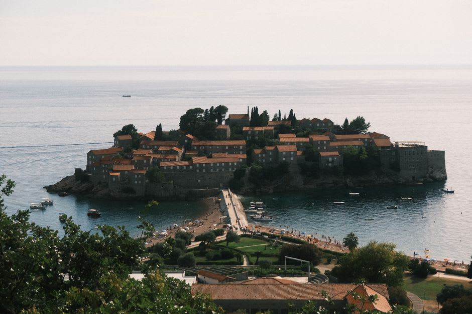 Narrow sandy isthmus connecting Sveti Stefan to the mainland at sunset