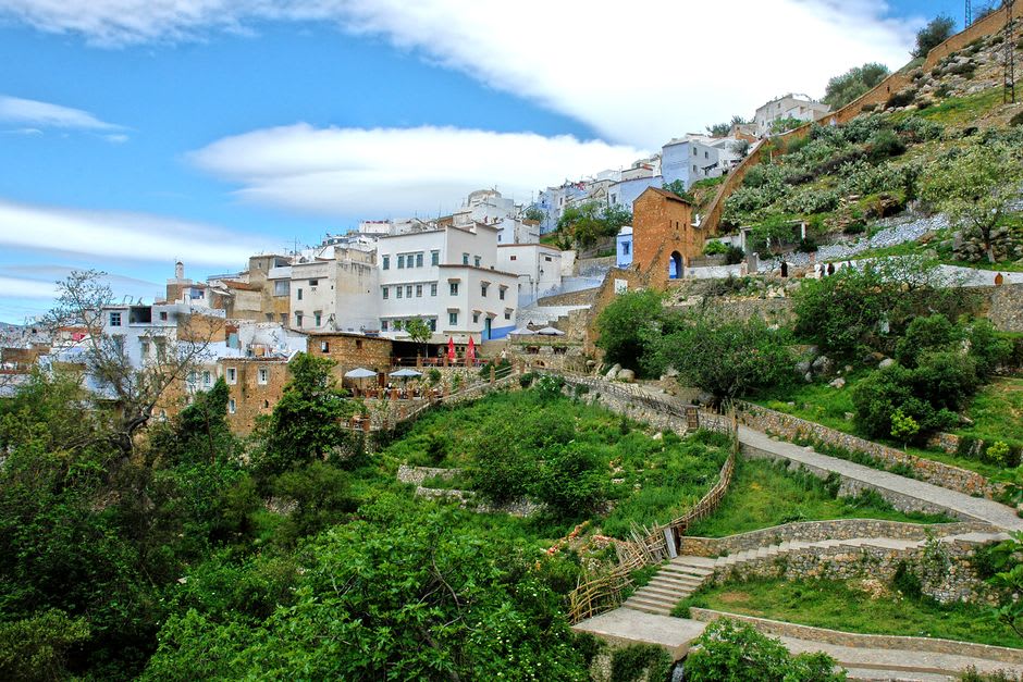 Arquitectura en la ladera de Chefchaouen con edificios azules entre vegetación exuberante, Marruecos
