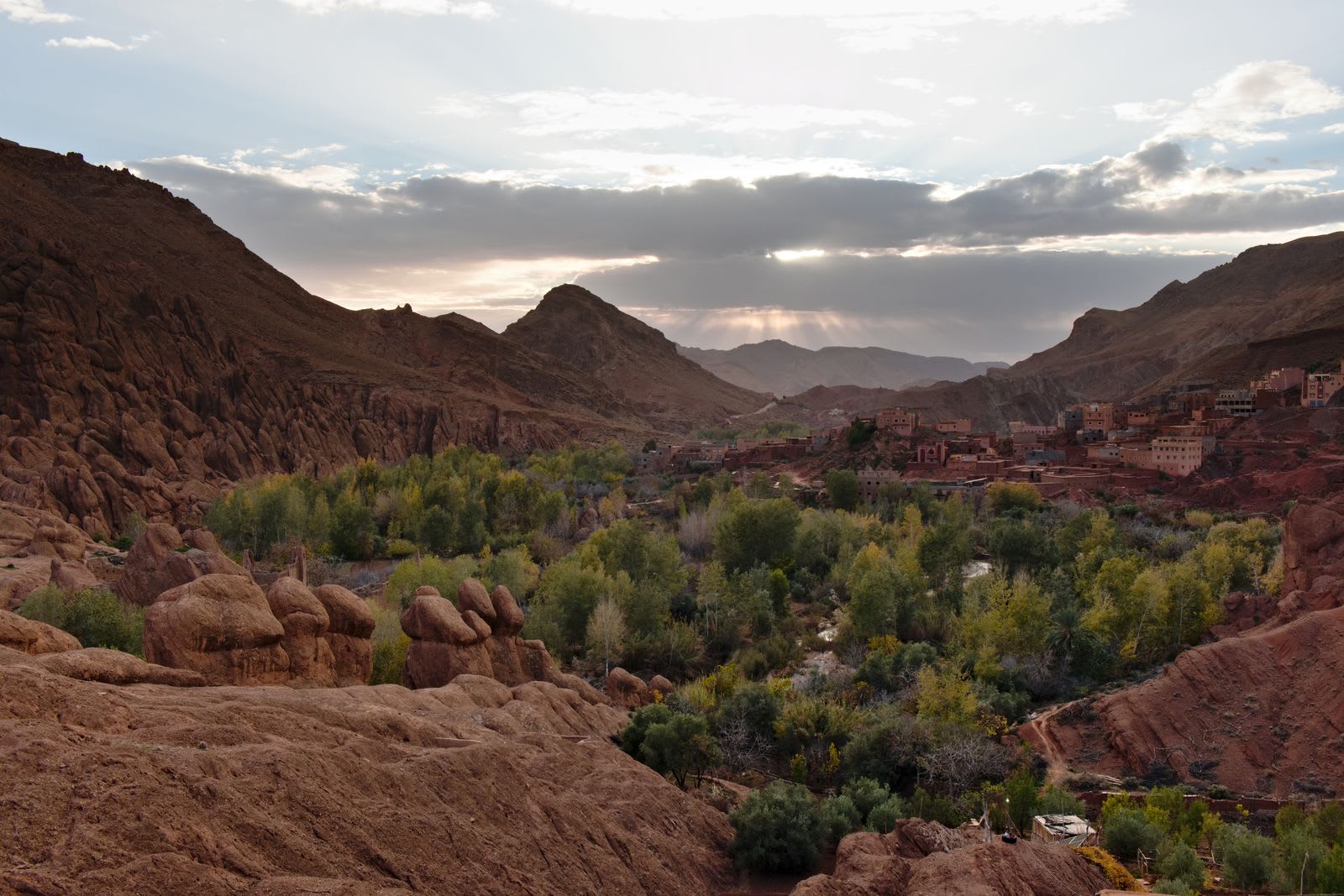 Gargantas del Dadés al atardecer, vegetación exuberante bajo las paredes rojas del cañón con un cielo crepuscular