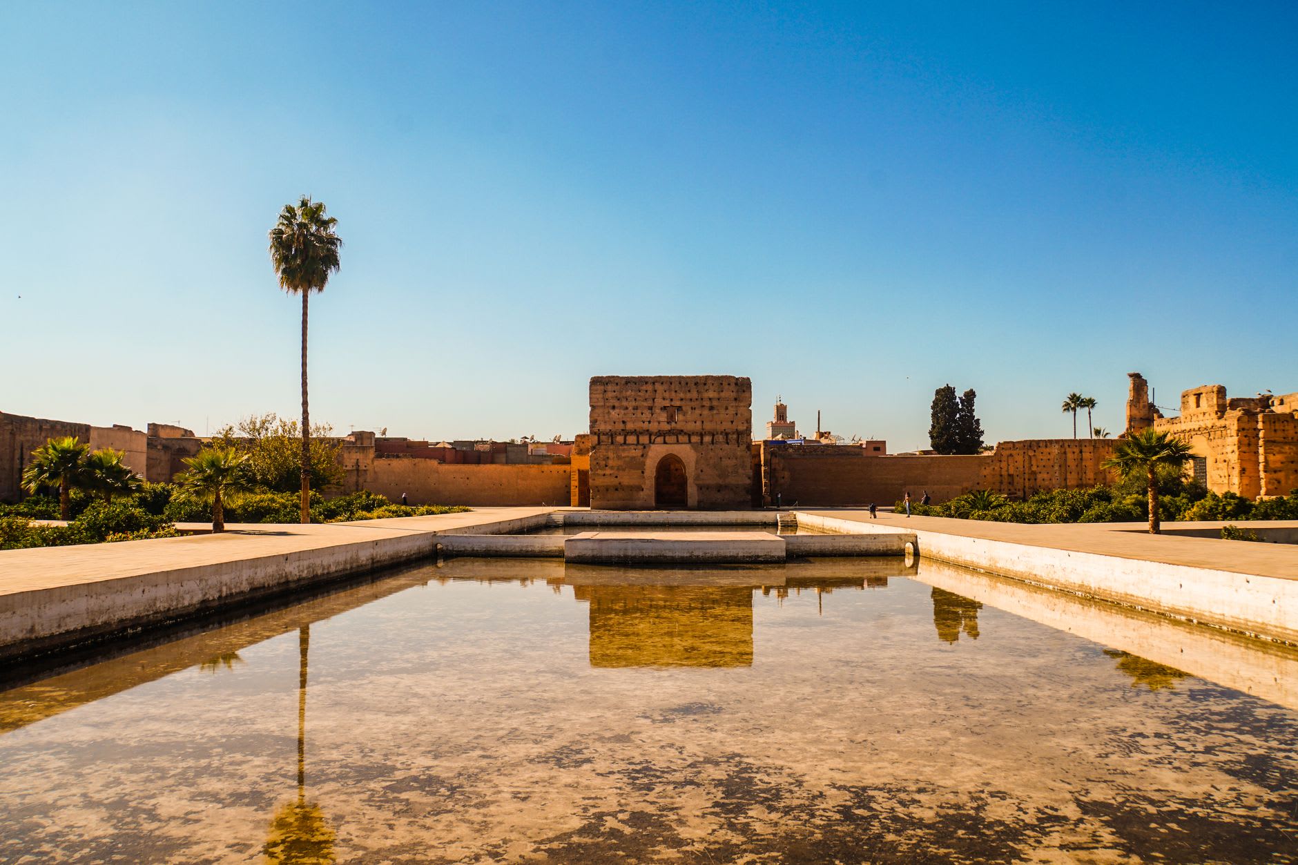 El Palacio El Badi en Marrakech con su estanque reflectante bajo un cielo azul abierto