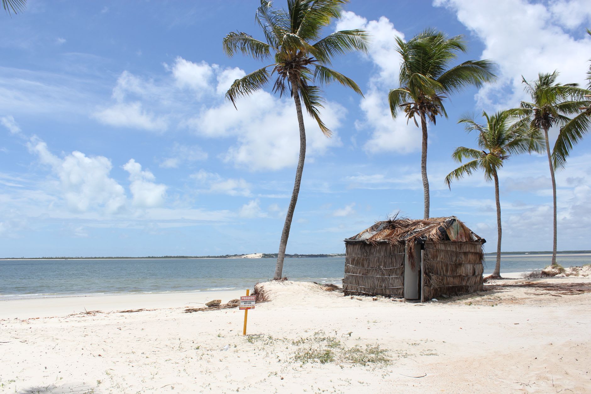A traditional wooden dhow with a triangular sail anchored in turquoise shallows off Ilha de Moçambique at golden hour
