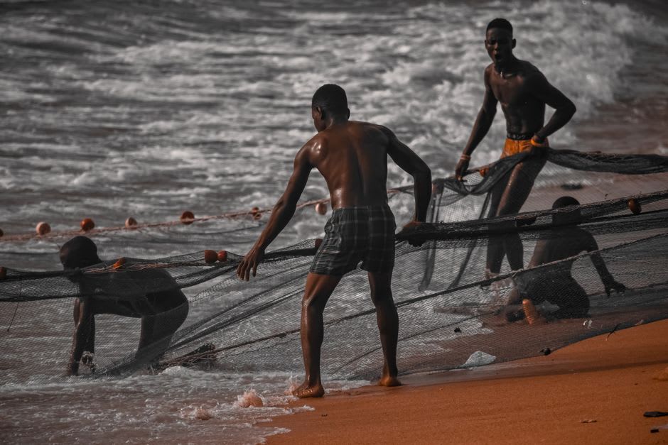 Fishermen hauling in a net at sunset on Xai-Xai beach