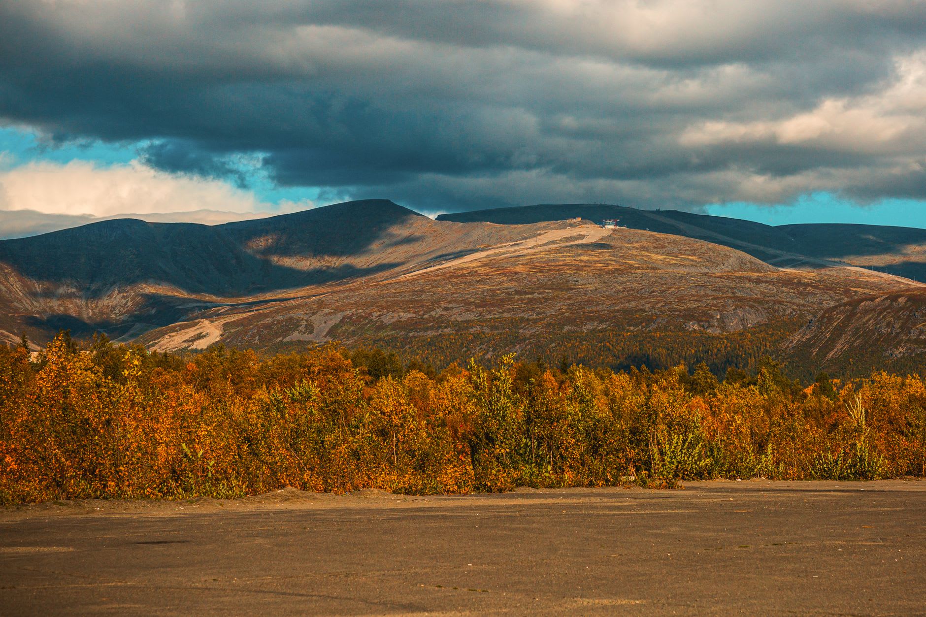 The ski slopes above Kirovsk with the Khibiny plateau visible beyond, runs carved through snowfields under a pale Arctic sky
