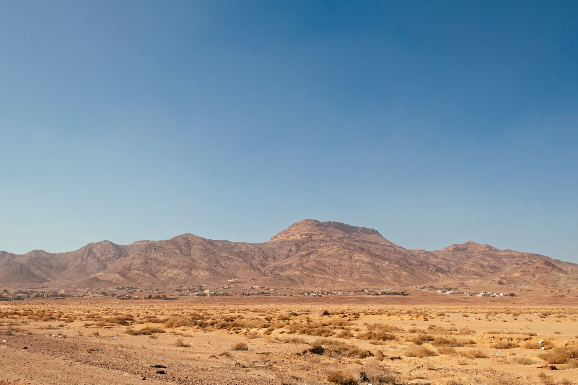 Desert wilderness trail through sandstone and sparse scrub leading away from Petra toward Jabal Haroun's white-domed summit