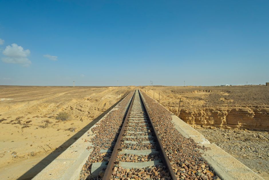 L'ancienne gare ottomane du chemin de fer du Hedjaz à Ma'an, des arches de pierre usées à côté d'un tronçon rouillé de voie étroite disparaissant dans le désert