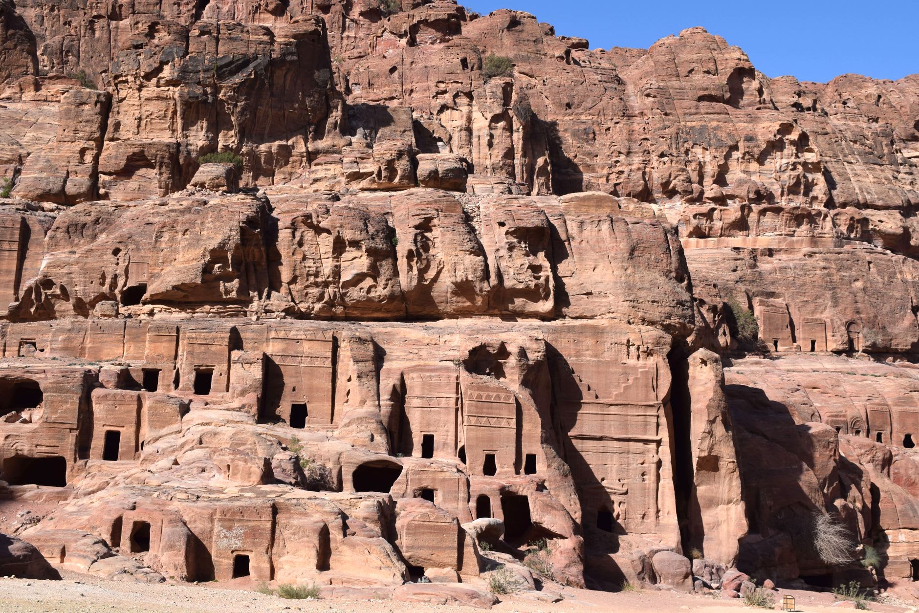 Swirling banded sandstone walls inside the Urn Tomb chamber, layers of maroon, cream and violet flowing through the carved rock