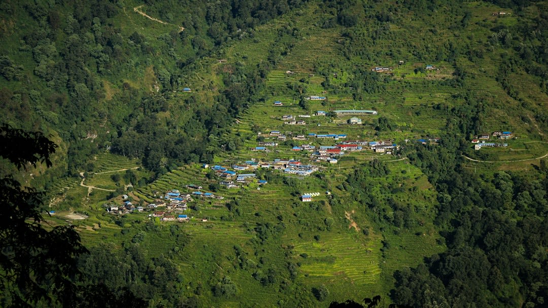 Callejuela empedrada a través del pueblo de Ghandruk con casas de tejado de pizarra y banderas de oración colgadas por encima
