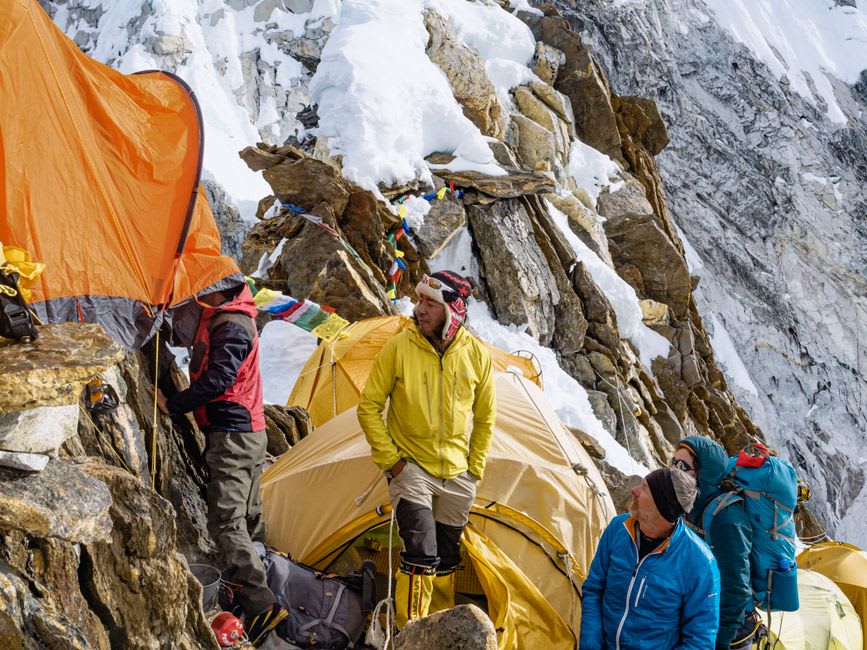 Trekkers crossing a suspension bridge over a glacial river deep in rhododendron forest on the approach to Kanchenjunga