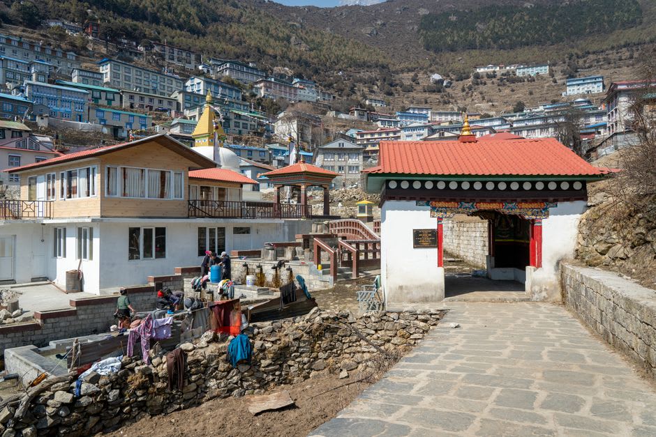 Weathered wooden window carvings on a traditional Sherpa house in Tarkeghyang with prayer flags strung across the alley